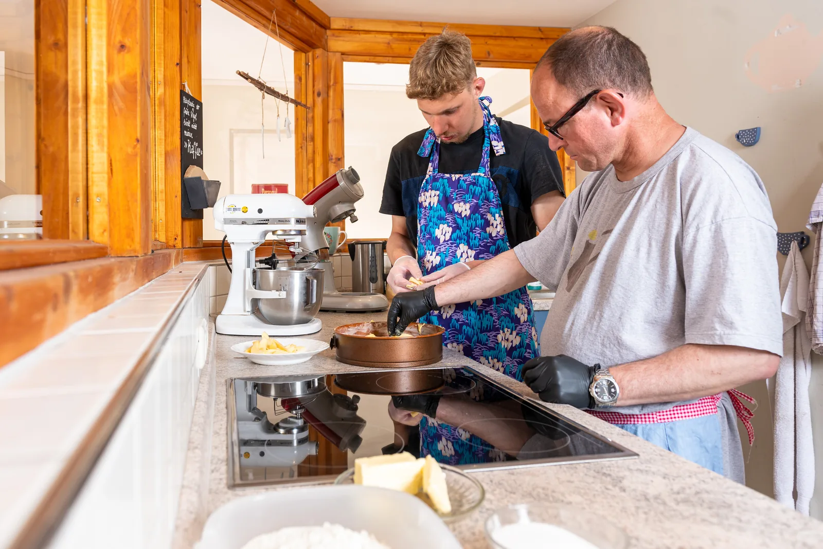 Bewohner und Betreuer backen gemeinsam einen Kuchen in der Wohnküche