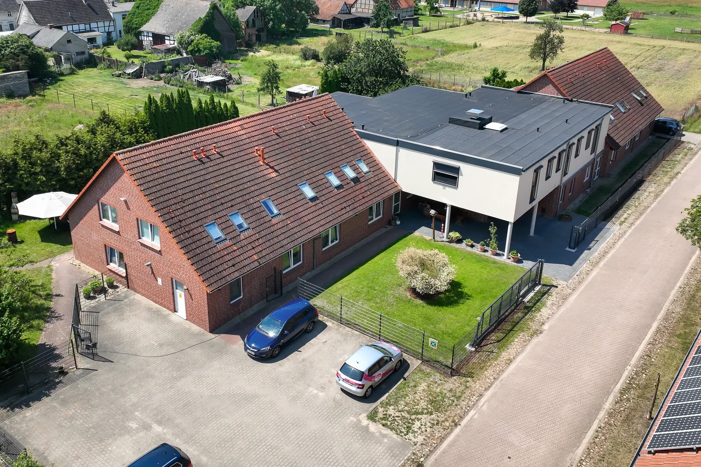 Luftbild von Haus Mechau, Backsteinhaus mit modernem Anbau und Parkplatz